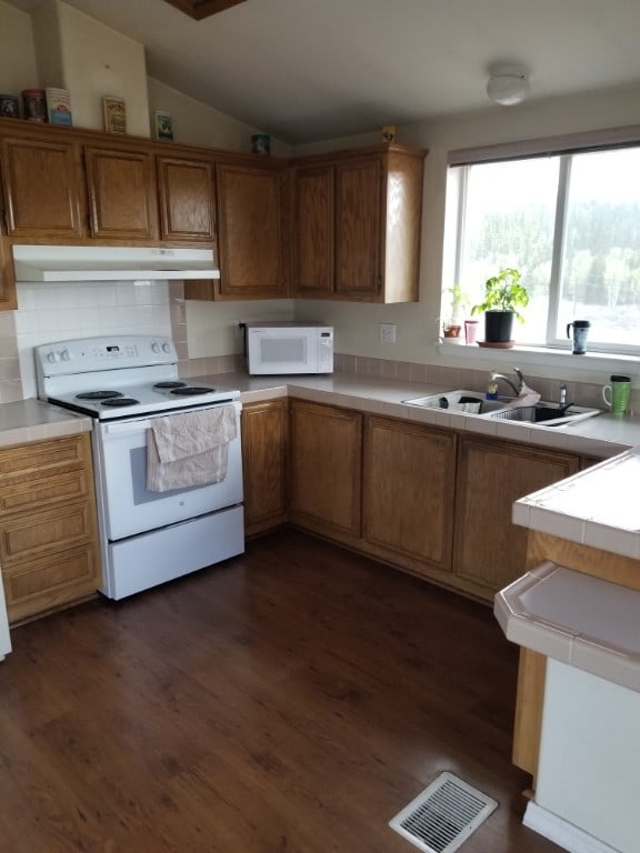 kitchen featuring lofted ceiling, sink, dark hardwood / wood-style floors, and white appliances