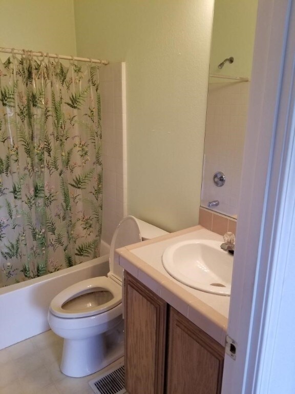 full bathroom with vanity, shower / bathtub combination with curtain, and toilet