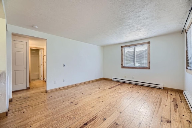 empty room with a baseboard radiator, light hardwood / wood-style floors, and a textured ceiling