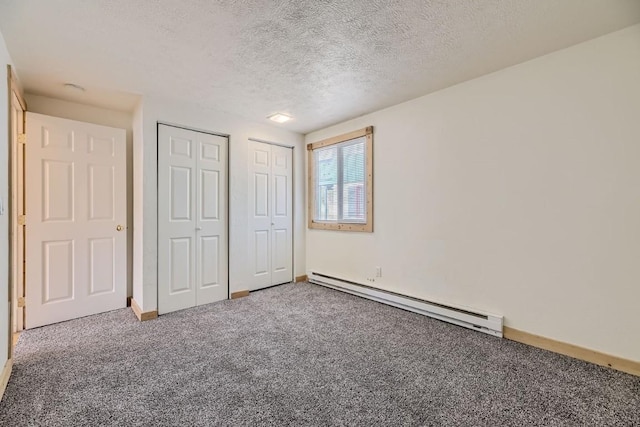 unfurnished bedroom featuring a textured ceiling, a baseboard radiator, multiple closets, and carpet flooring