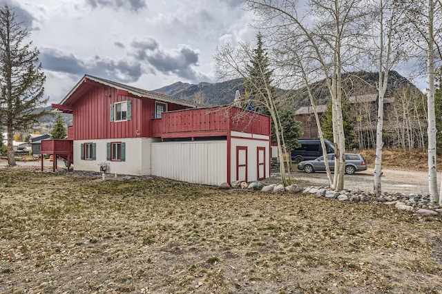 view of side of property featuring a deck with mountain view and a lawn