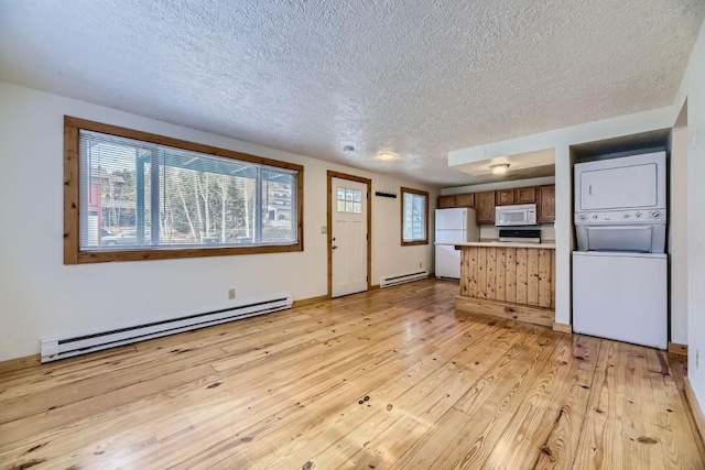 kitchen featuring stacked washer and dryer, a baseboard heating unit, white appliances, and light hardwood / wood-style flooring