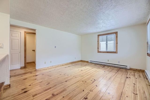 unfurnished room featuring a textured ceiling, baseboard heating, and light hardwood / wood-style floors