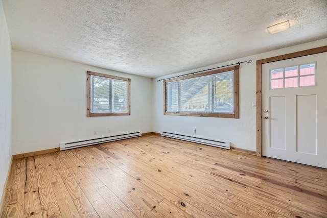 foyer entrance with baseboard heating, light hardwood / wood-style floors, and a textured ceiling