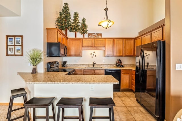 kitchen with pendant lighting, brown cabinets, a sink, a peninsula, and black appliances