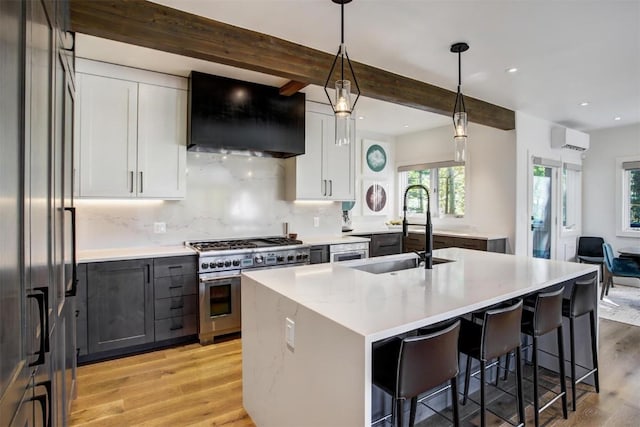 kitchen with white cabinetry, wall chimney range hood, beamed ceiling, decorative light fixtures, and range with two ovens