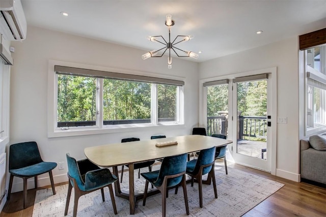 dining room featuring a wall unit AC, a chandelier, and hardwood / wood-style flooring