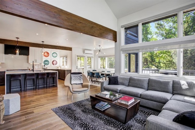 living room with light hardwood / wood-style flooring, beamed ceiling, high vaulted ceiling, a wall unit AC, and a chandelier