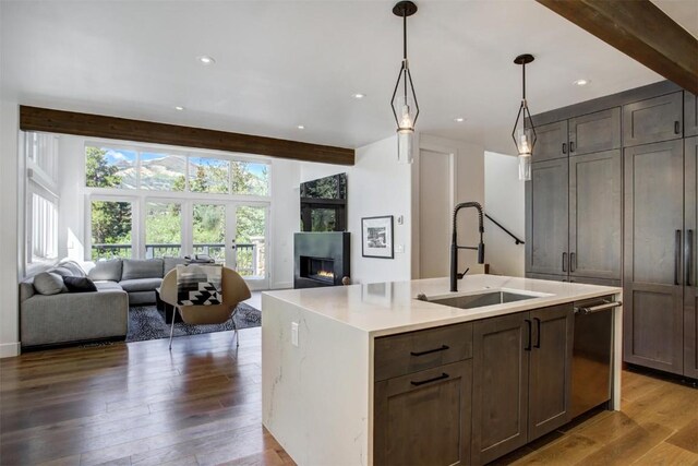 kitchen featuring a center island with sink, dishwasher, beam ceiling, and sink