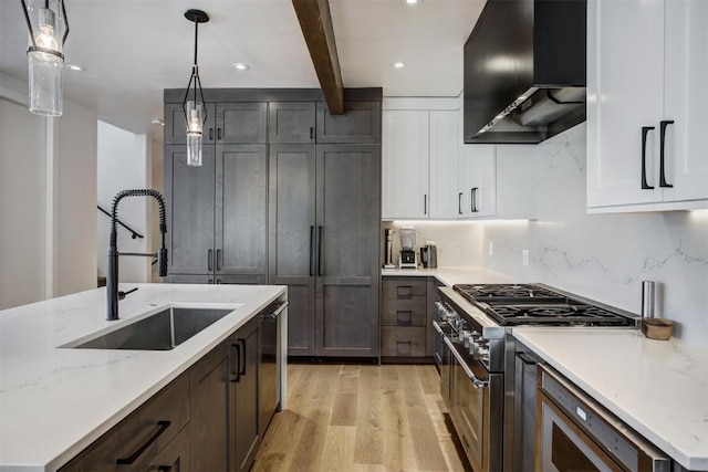 kitchen with white cabinets, wall chimney range hood, hanging light fixtures, and stainless steel range