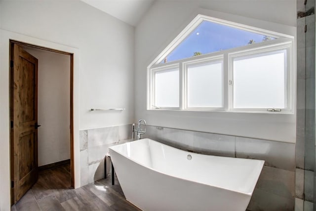 bathroom featuring hardwood / wood-style floors, lofted ceiling, shower with separate bathtub, and tile walls