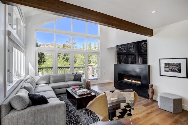 living room featuring beamed ceiling and light hardwood / wood-style floors