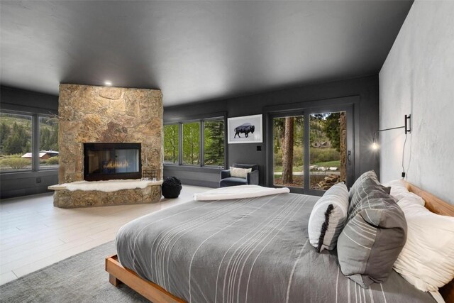 bedroom with access to outside and a stone fireplace