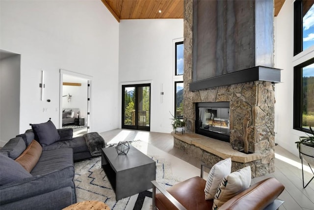 living room featuring a fireplace, wood ceiling, a high ceiling, and light wood-type flooring