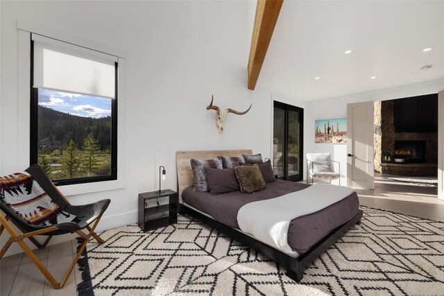 bedroom with beamed ceiling and a large fireplace