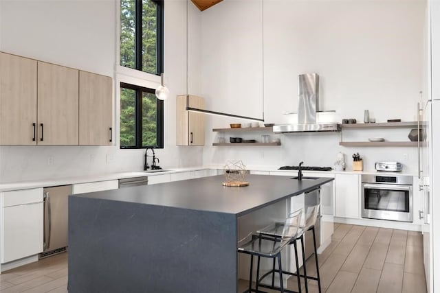 kitchen featuring a center island, a towering ceiling, exhaust hood, and appliances with stainless steel finishes