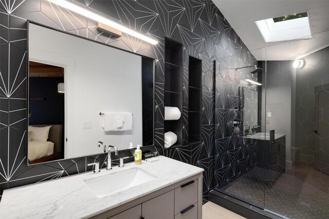 bathroom featuring vanity, a shower with shower door, tile walls, and a skylight