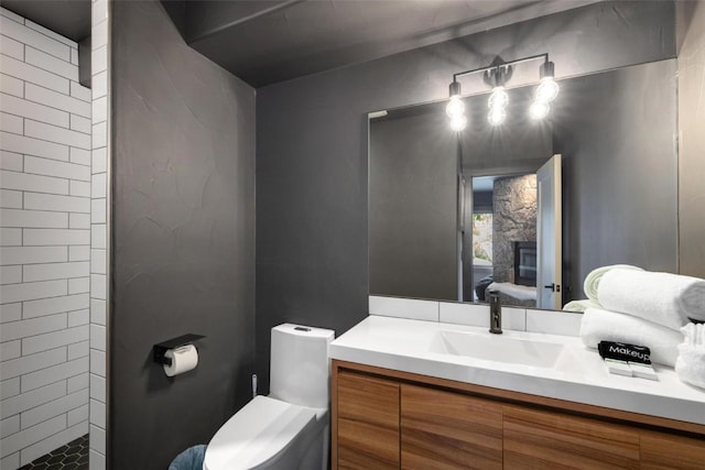 bathroom with a tile shower, vanity, and toilet