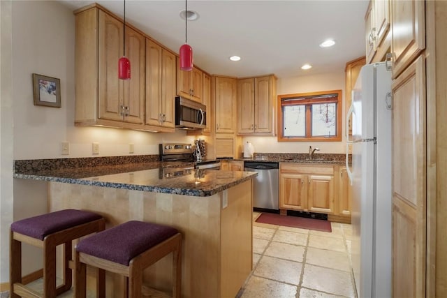 kitchen featuring a breakfast bar, a sink, recessed lighting, appliances with stainless steel finishes, and a peninsula