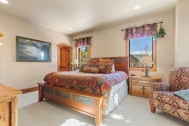 bedroom featuring light carpet, recessed lighting, arched walkways, and baseboards