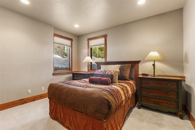 bedroom featuring recessed lighting, light colored carpet, baseboards, and a textured wall