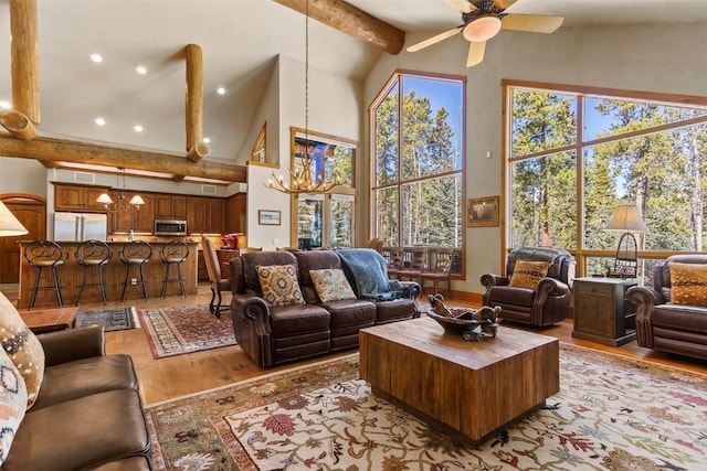 living area featuring beamed ceiling, ceiling fan with notable chandelier, high vaulted ceiling, and light wood-style floors