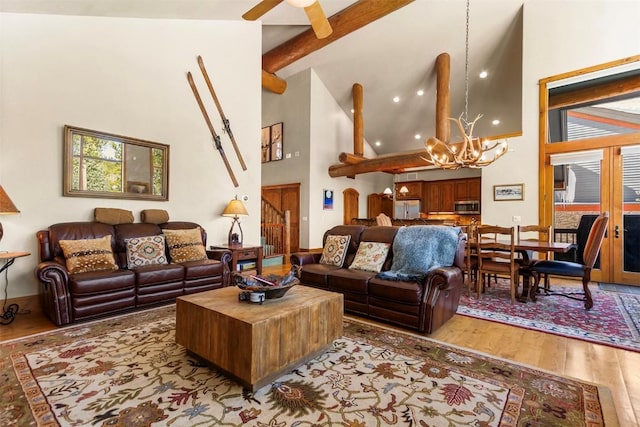 living area with beam ceiling, ceiling fan with notable chandelier, high vaulted ceiling, and wood finished floors