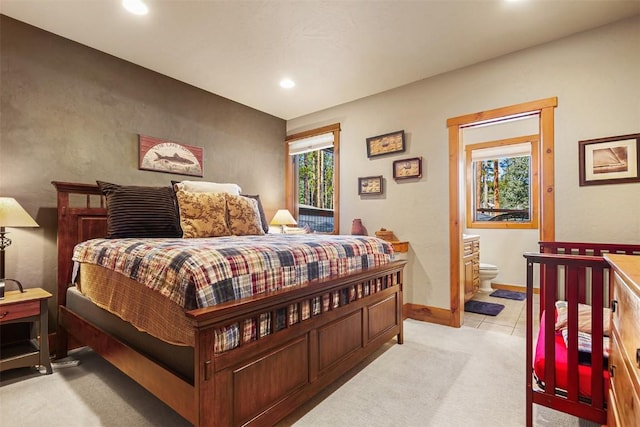 bedroom with recessed lighting, baseboards, light carpet, and ensuite bathroom