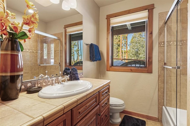 full bath featuring vanity, toilet, baseboards, and a wealth of natural light