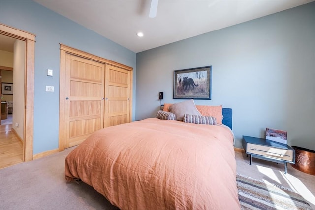 bedroom featuring ceiling fan, a closet, and light carpet