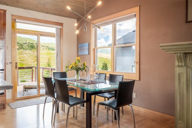 dining room with vaulted ceiling, wood ceiling, a wealth of natural light, and light hardwood / wood-style flooring