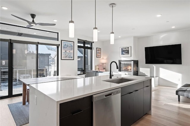 kitchen with ceiling fan, a kitchen island with sink, sink, decorative light fixtures, and dishwasher