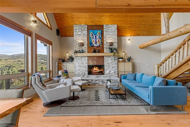 living room featuring beam ceiling, a healthy amount of sunlight, a stone fireplace, and high vaulted ceiling