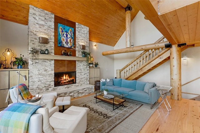 living room featuring wood ceiling, light hardwood / wood-style flooring, a stone fireplace, and high vaulted ceiling