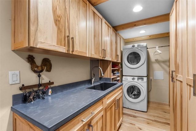 laundry area with light wood-type flooring, stacked washer and clothes dryer, and sink