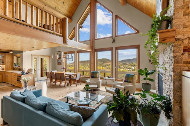 living room featuring high vaulted ceiling, light wood-type flooring, wood ceiling, and a mountain view