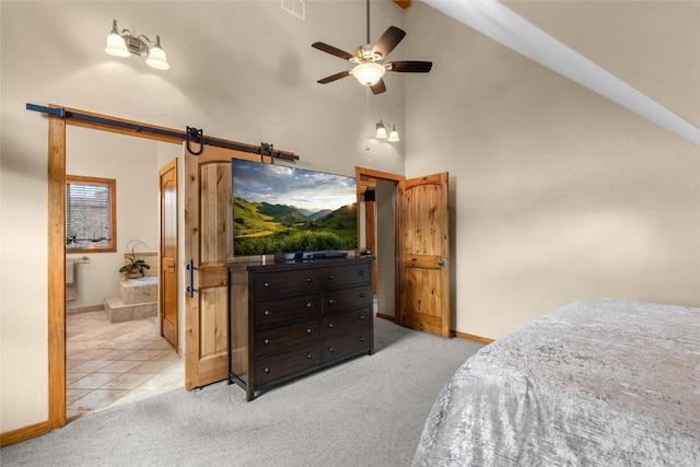 bedroom with ceiling fan, a barn door, light colored carpet, lofted ceiling, and connected bathroom