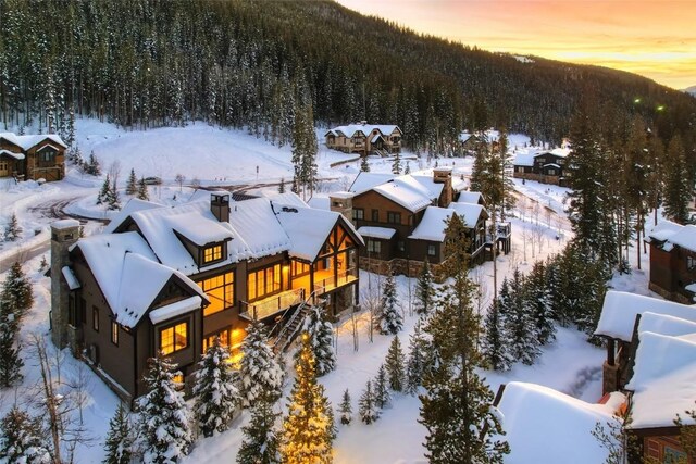 snow covered back of property featuring a mountain view