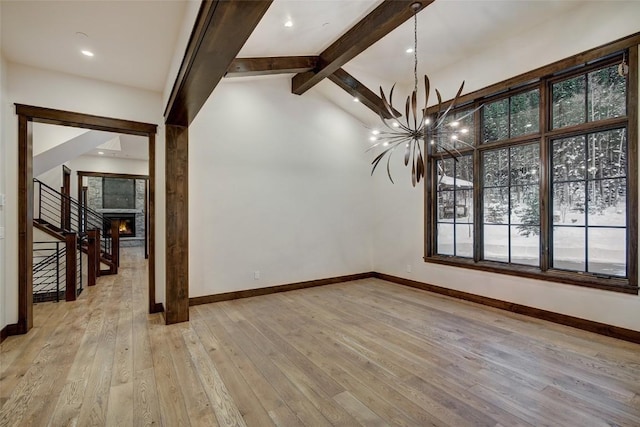 interior space with an inviting chandelier, a stone fireplace, lofted ceiling with beams, and light hardwood / wood-style floors