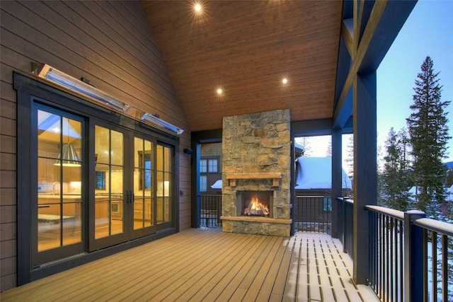 deck at dusk featuring an outdoor stone fireplace