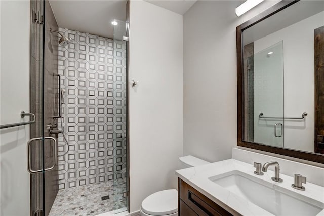 bathroom featuring vanity, a shower with door, and toilet