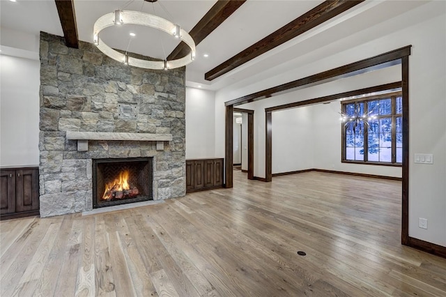 unfurnished living room with a fireplace, beamed ceiling, and light wood-type flooring