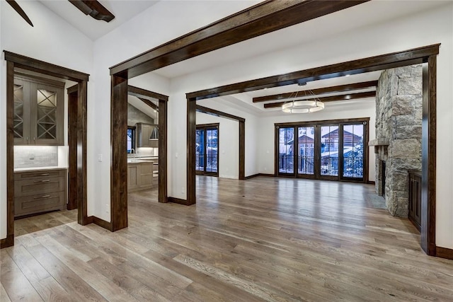 interior space featuring hardwood / wood-style floors, a stone fireplace, and beamed ceiling