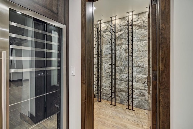 wine area with beverage cooler and light wood-type flooring