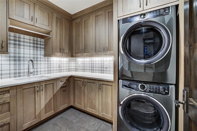 laundry area with cabinets, stacked washer / drying machine, and sink