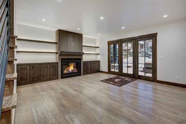 unfurnished living room featuring a fireplace, light hardwood / wood-style flooring, and french doors