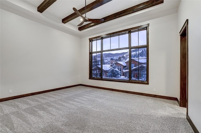 carpeted empty room featuring beamed ceiling, ceiling fan, and a mountain view