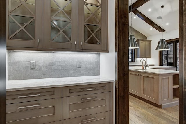 kitchen featuring sink, lofted ceiling with beams, decorative backsplash, light hardwood / wood-style floors, and decorative light fixtures