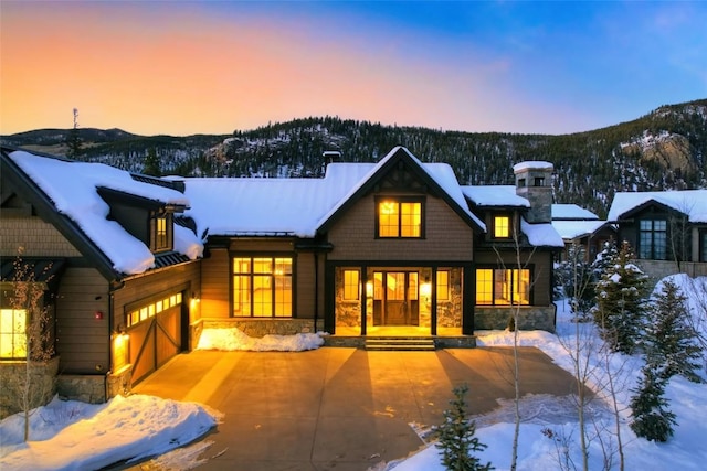 snow covered property with a garage and a mountain view