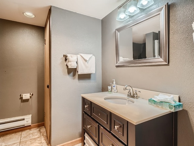 bathroom featuring a baseboard heating unit, tile patterned flooring, vanity, and baseboards